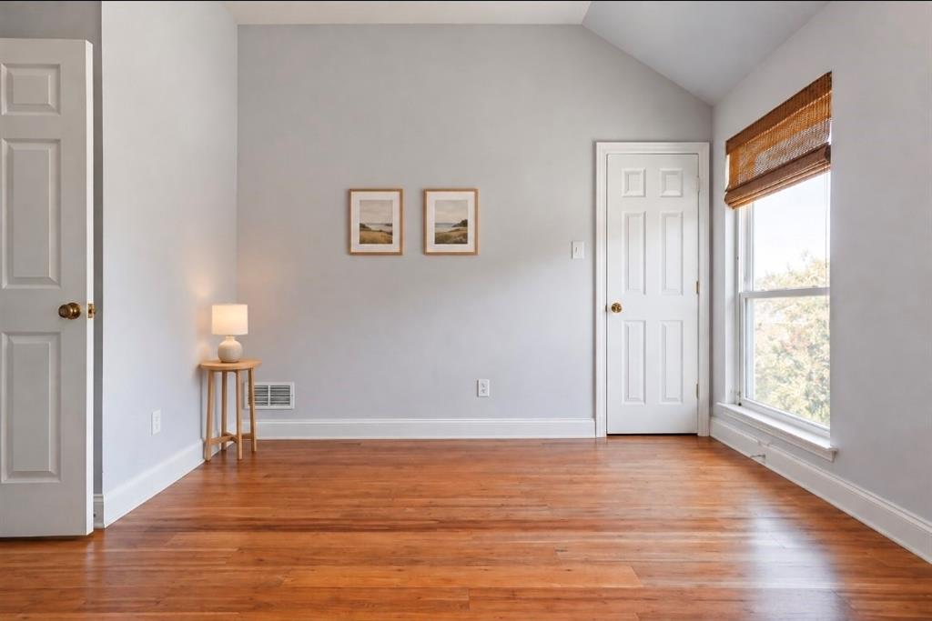Neutral interior space featuring wood-finish flooring, crisp white trim, two six-panel doors, and a large window with natural light