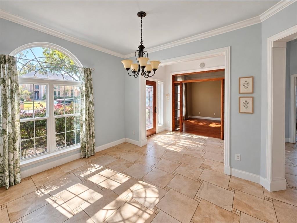 Arched window, tile flooring, crown molding, chandelier, and stained-wood cased entry Arched window, tile flooring, crown molding, chandelier, and stained-wood cased entry