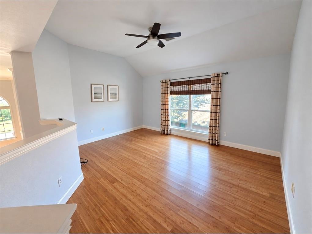 Vaulted ceilings, wood-finish flooring, and a central ceiling fan