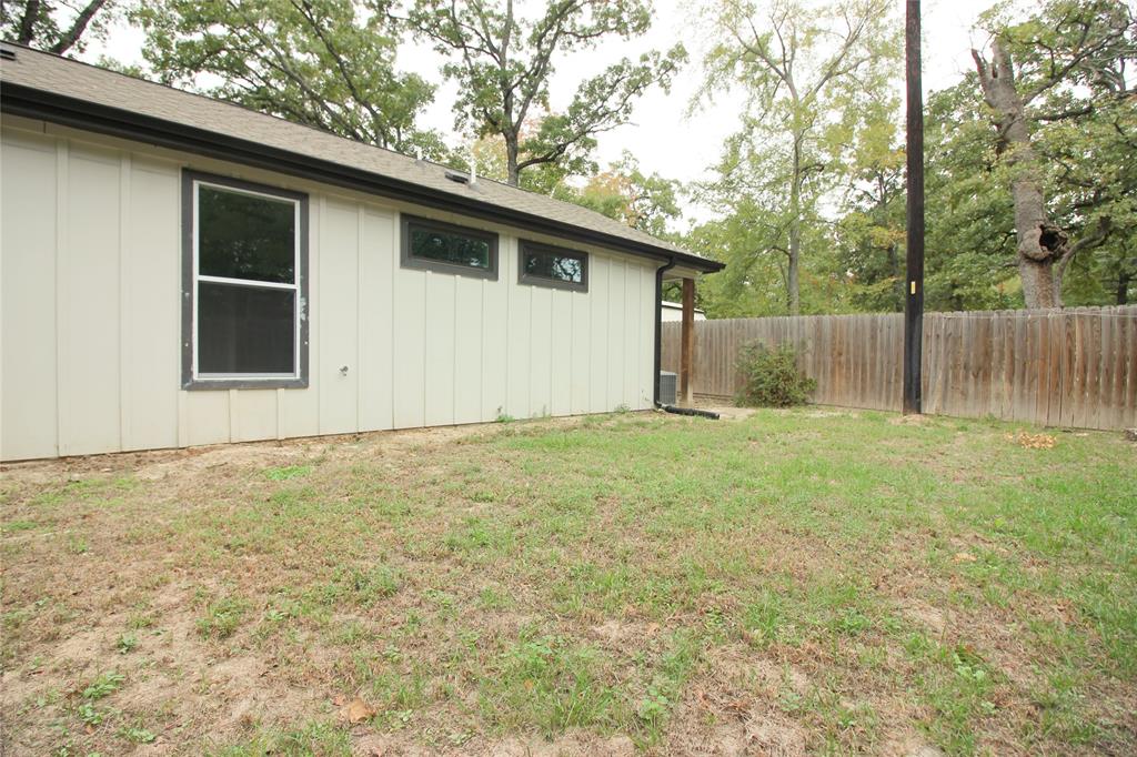 Exterior featuring board-and-batten siding, horizontal and vertical windows with dark framing, and a wood privacy fence