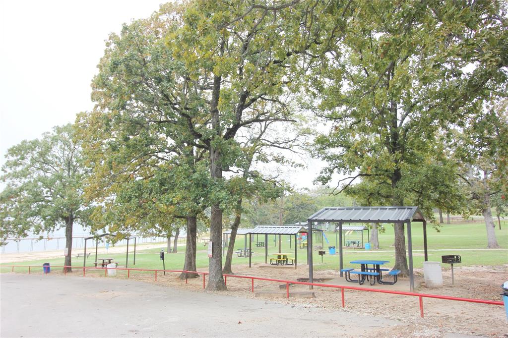 Expansive grounds featuring mature oak trees, paved pathways, and multiple covered metal pavilions