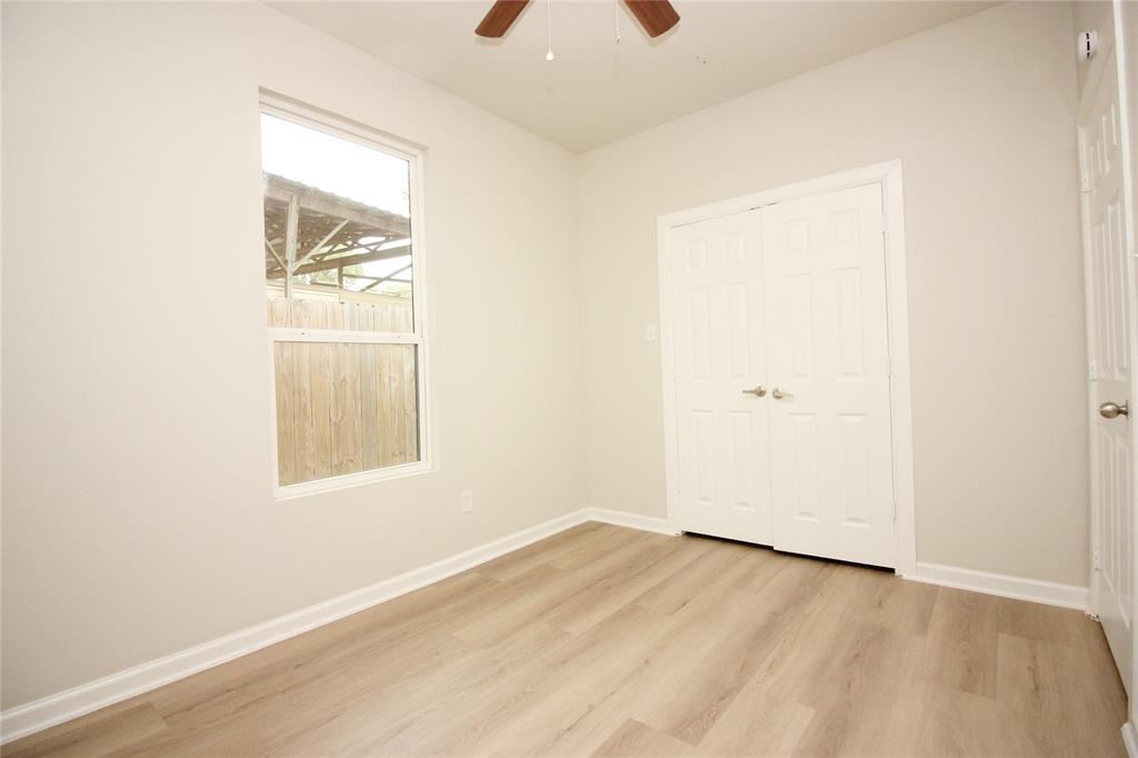Neutral interior featuring wood-finish flooring, a double-panel closet with brushed nickel hardware, and a ceiling fan