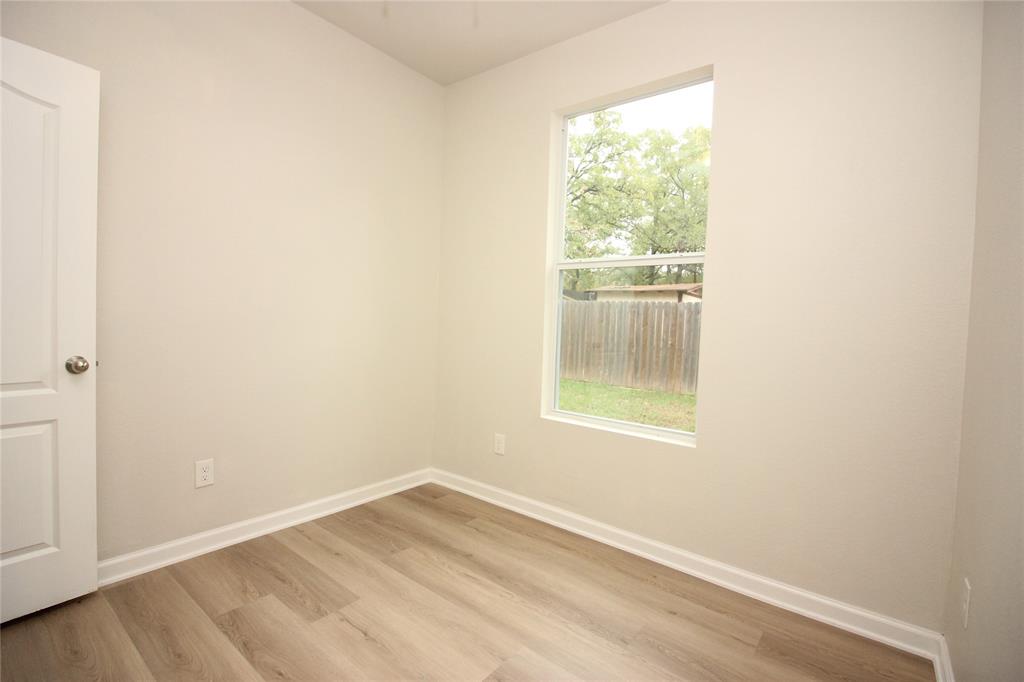 Neutral interior featuring light-toned wood-finish flooring, crisp painted walls, a single-hung window, and a paneled interior door with a brushed metallic knob