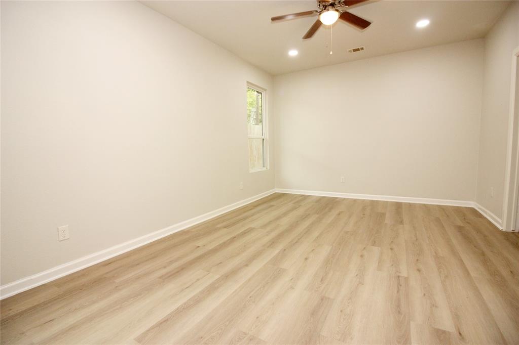 Neutral-toned interior featuring wood-finish flooring, recessed lighting, a ceiling fan with integrated light, and a single-pane window