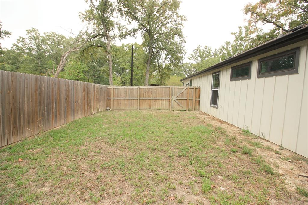 Backyard featuring vertical board siding, a wood privacy fence, and mature trees