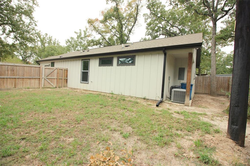 Exterior featuring vertical siding, a wood privacy fence, and mature trees