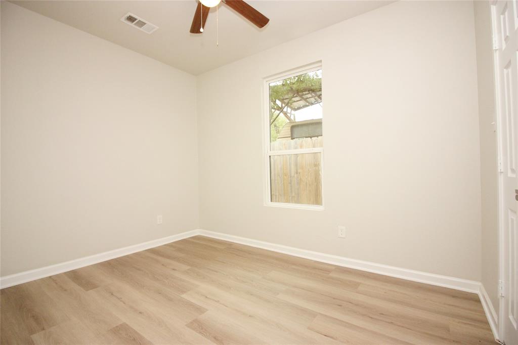 Neutral-toned interior featuring wood-finish flooring, a single-pane window, and a ceiling fan with integrated lighting