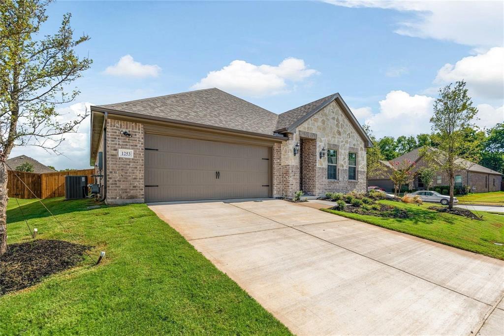 Exterior facade featuring a combination of brick and stone masonry, a multi-car attached garage, and a concrete driveway