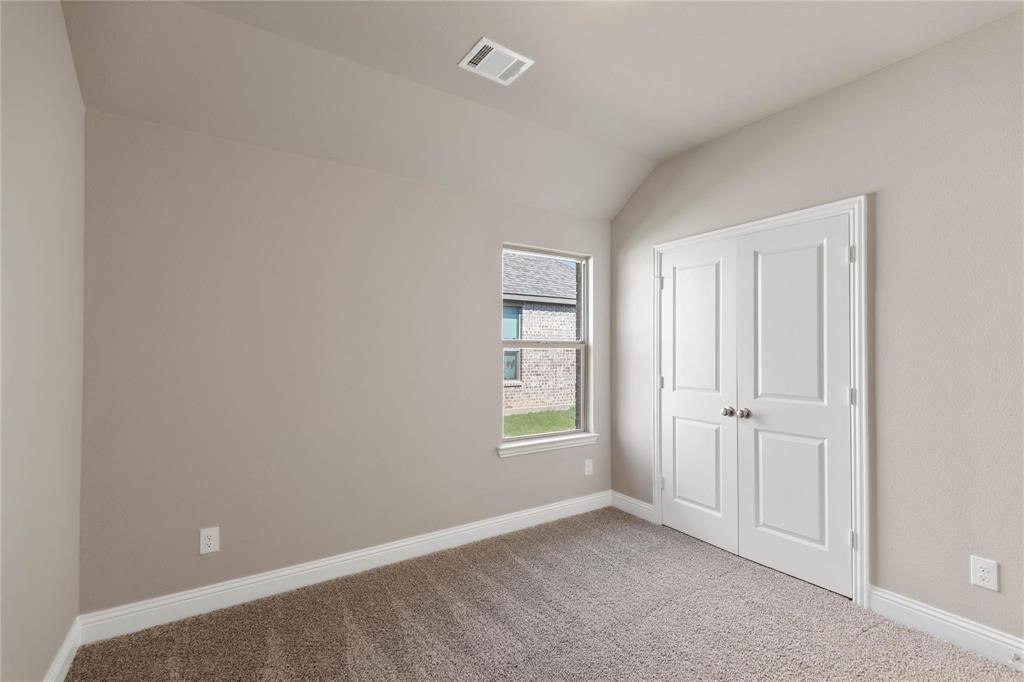 Vaulted ceiling room featuring neutral wall paint, carpeted flooring, a single window, and a white double-door closet