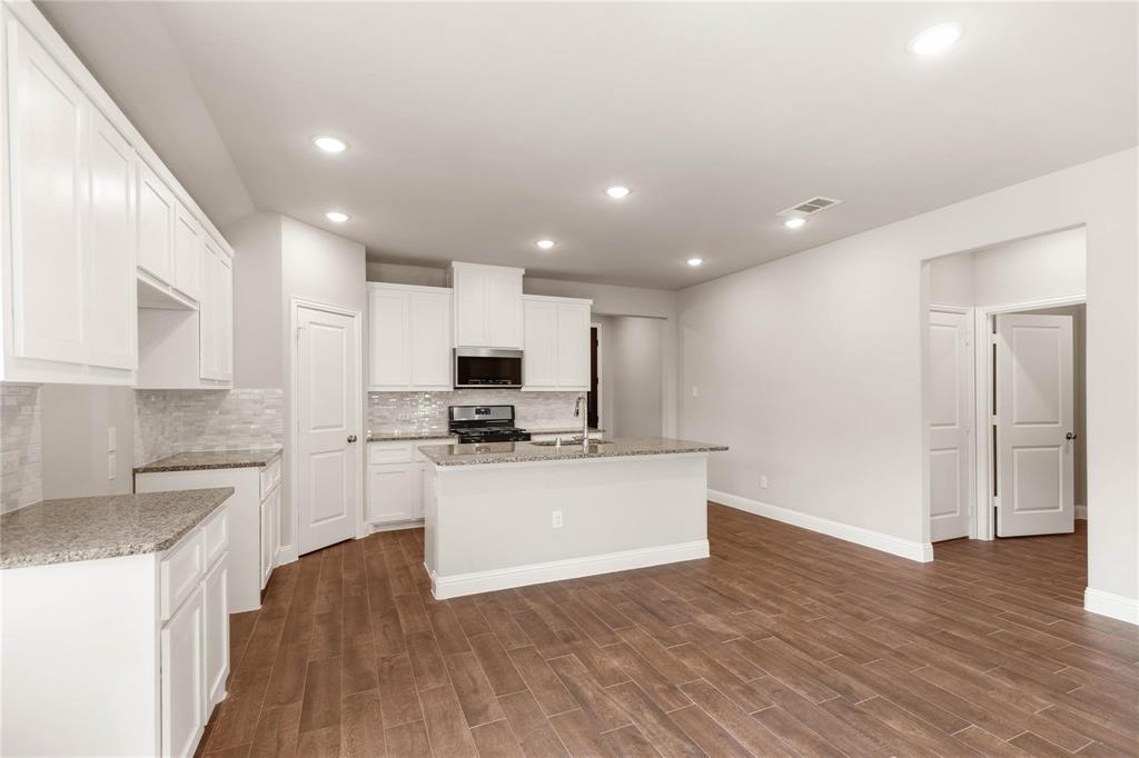 Kitchen featuring white cabinetry, stone-finish countertops, a central island, recessed lighting, and wood-finish flooring