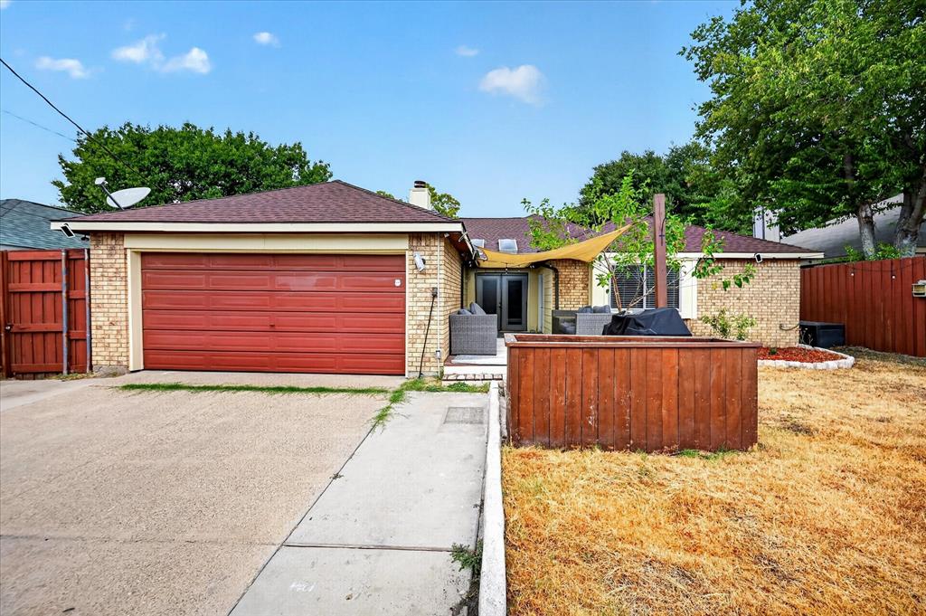 Brick exterior facade with an attached two-car garage, concrete driveway, and solid wood privacy fencing