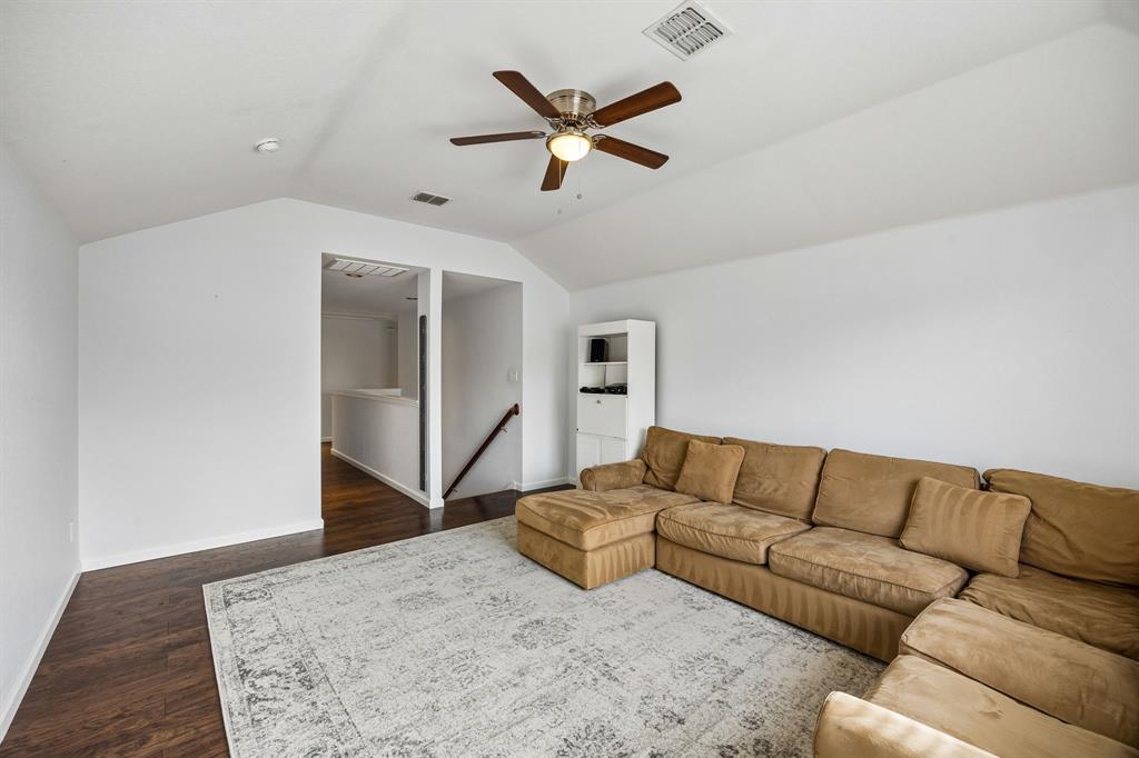This alternate view highlights the versatility of the upstairs living area, showcasing its vaulted ceiling, expansive wall space, and attractive wood-look flooring. The open layout provides plenty of room to customize the space to suit a variety of needs, whether envisioned as a media room, playroom, home office, or additional gathering space.