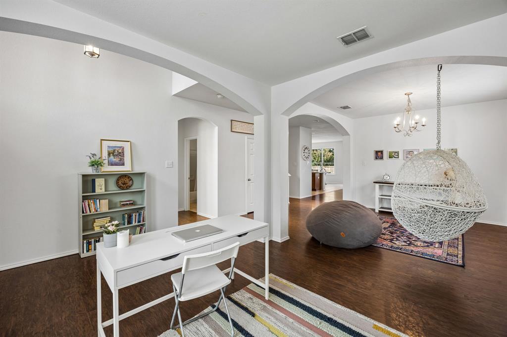 Another view of the thoughtfully designed office that showcases the home's versatile floor plan, with graceful archways connecting distinct living areas. The dedicated workspace, expansive openings, and warm wood-look flooring create a harmonious setting that balances productivity, relaxation, and everyday functionality.