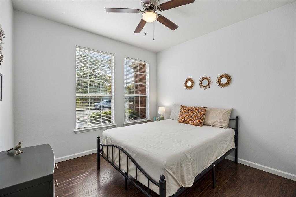 Natural light fills this inviting 1st floor bedroom through two windows overlooking the front of the home. Warm wood-look flooring, neutral walls, and a ceiling fan create a comfortable, versatile space. The room's practical layout and ample natural light make it well suited for a bedroom, guest room, or home office.