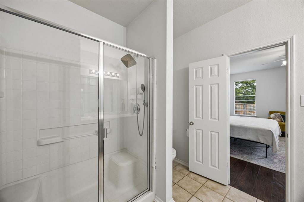 A glass-enclosed shower features tiled walls, chrome-finished fixtures, and a spacious interior designed for everyday comfort. The glass doors create an open feel while allowing light to flow throughout the bathroom. Conveniently attached to the primary bedroom, this ensuite offers a practical layout that you'll enjoy.