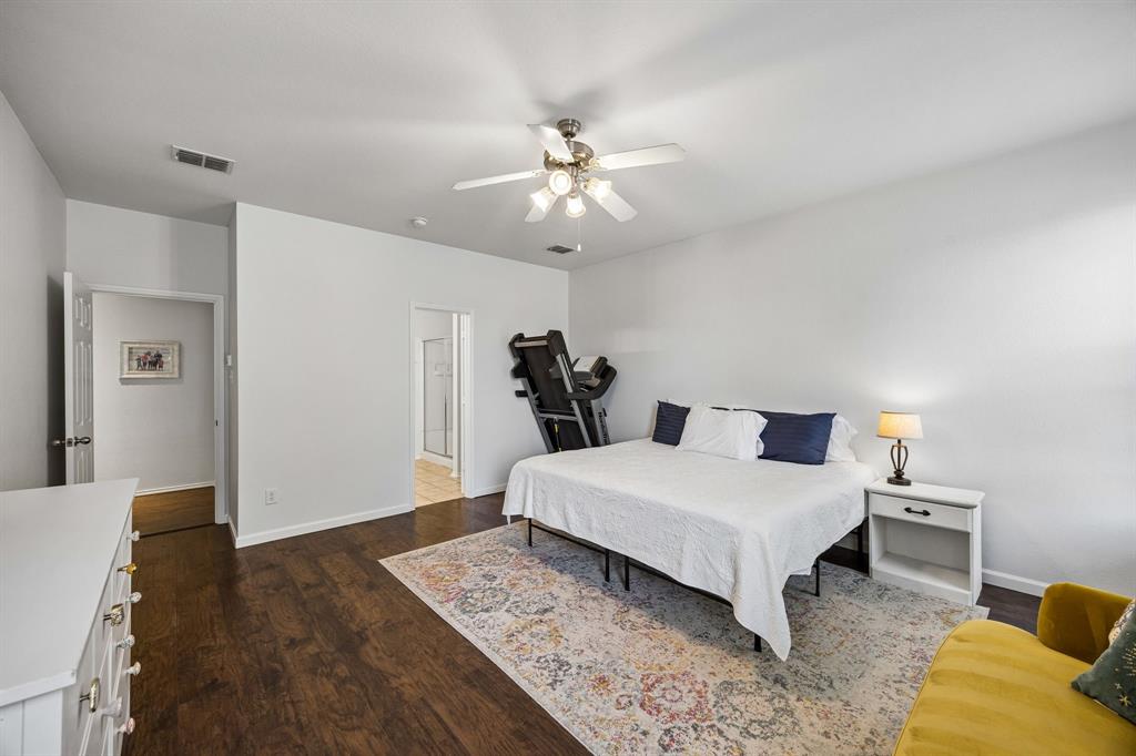 This generously sized primary bedroom with attached ensuite features warm wood-look flooring, neutral finishes, and a ceiling fan with integrated lighting. The room's spacious layout and understated finishes create a comfortable setting with room to make it your own.