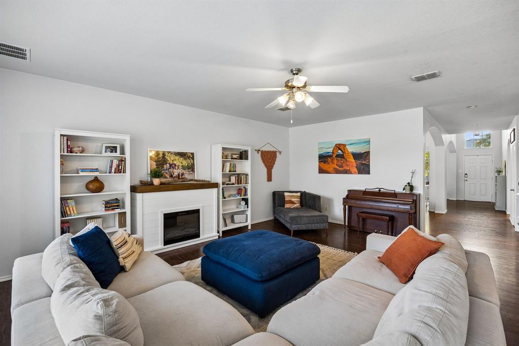 This inviting living area showcases the home's open layout, rich wood flooring, and bright, welcoming interior. A stylish fireplace with shelving adds architectural interest, while the adjoining entryway features graceful arched openings that enhance the home's character. The seamless flow between spaces creates a wonderful sense of connection throughout the main living areas.