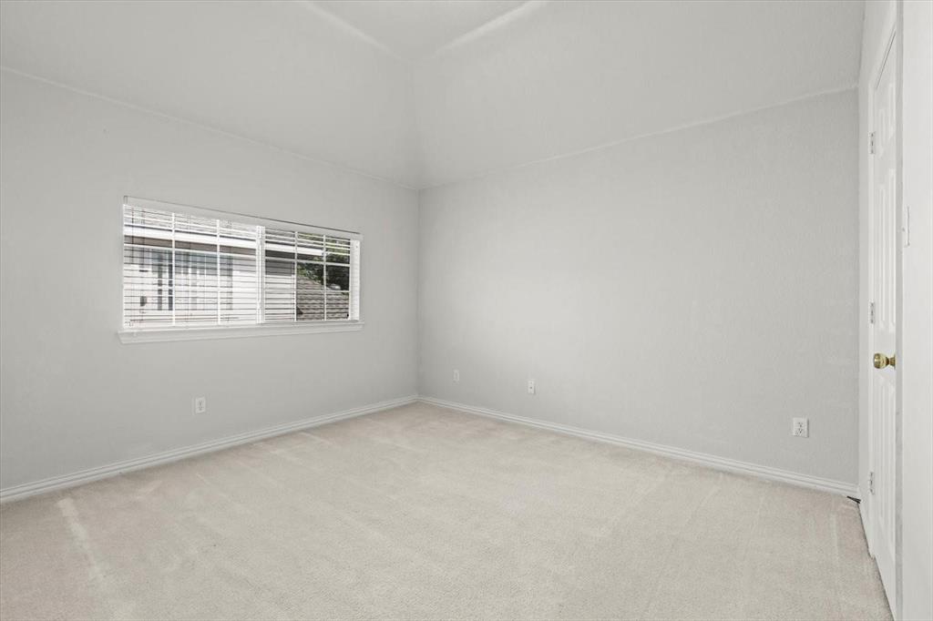Vaulted ceiling, neutral wall tones, wall-to-wall carpeting, and horizontal window blinds