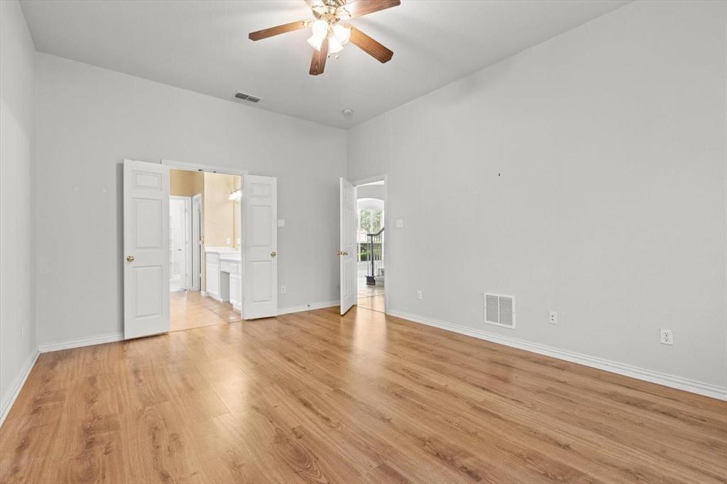 Interior room featuring high ceilings, wood-finish flooring, and a ceiling fan with integrated lighting