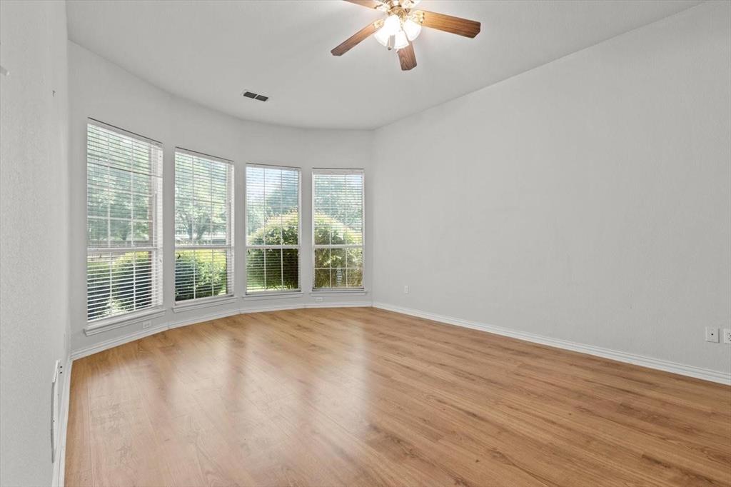 Bay window featuring four multi-pane windows, wood-finish flooring, and a ceiling-mounted light fixture with a central fan