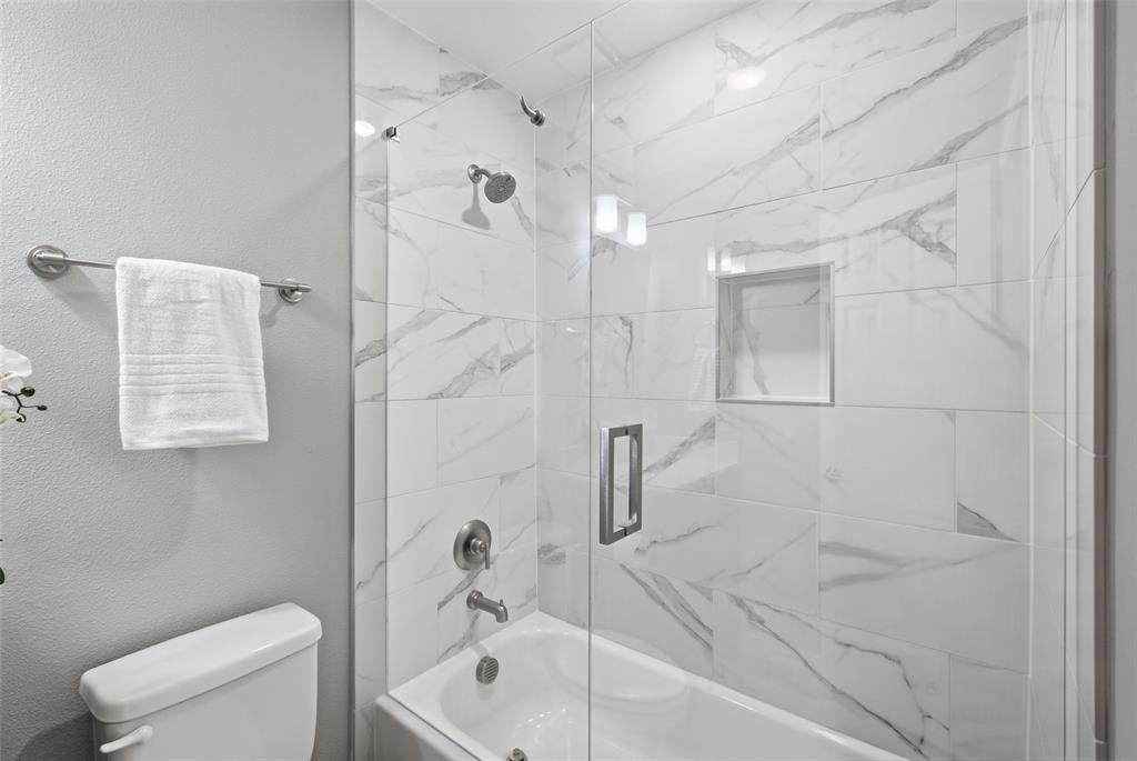The shower-tub combo has floor-to-ceiling marble-look tile, a built-in niche and frameless glass. Spa style for every day.