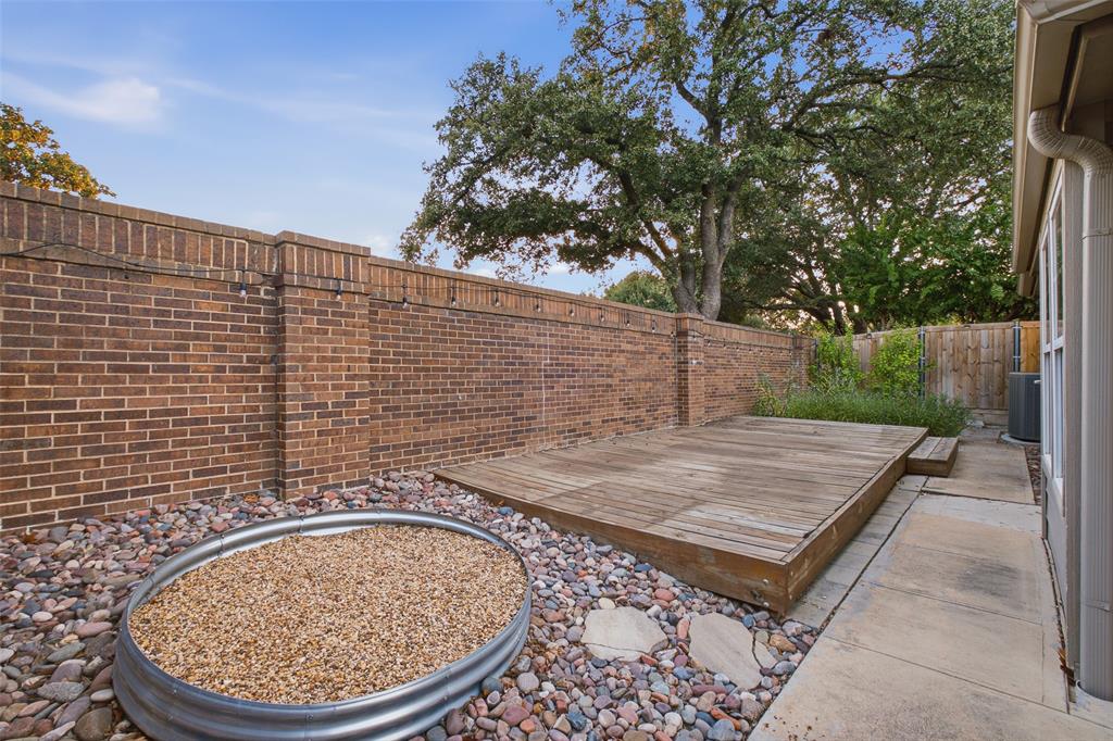 A brick privacy wall, a wood deck and a gravel fire-feature area surrounded by river rock and shaded by mature oaks. Your backyard escape.