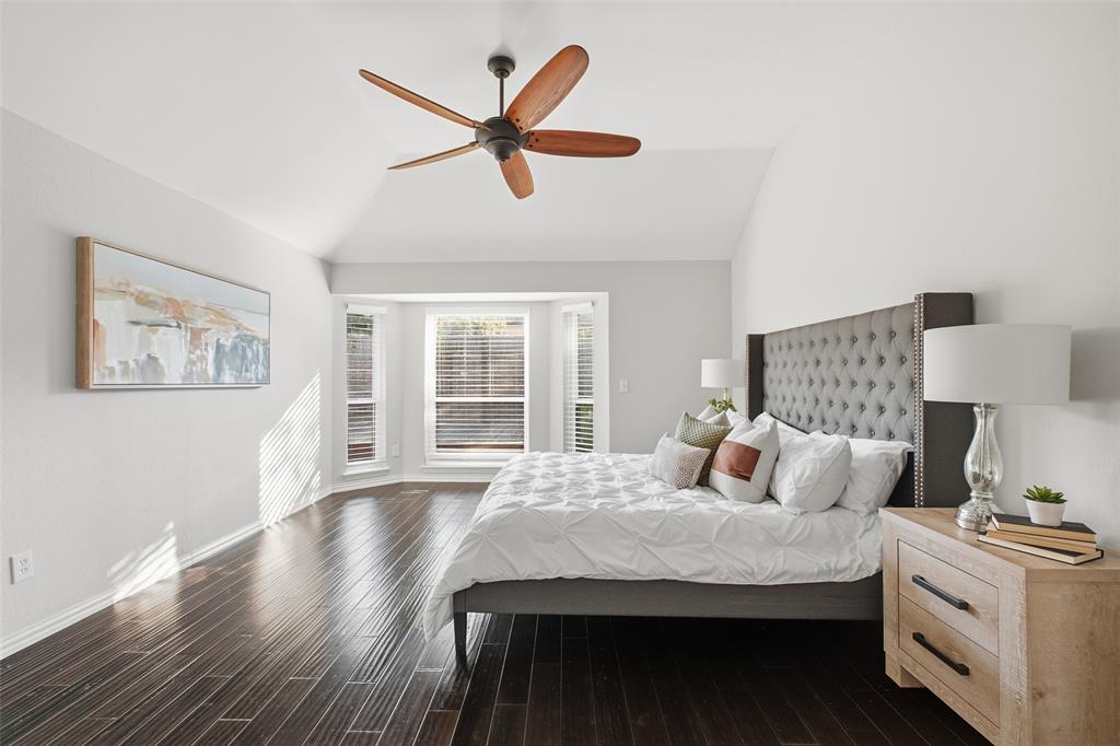 Your private retreat: the primary suite has a soaring vaulted ceiling, a sunny bay window and dark wood floors.