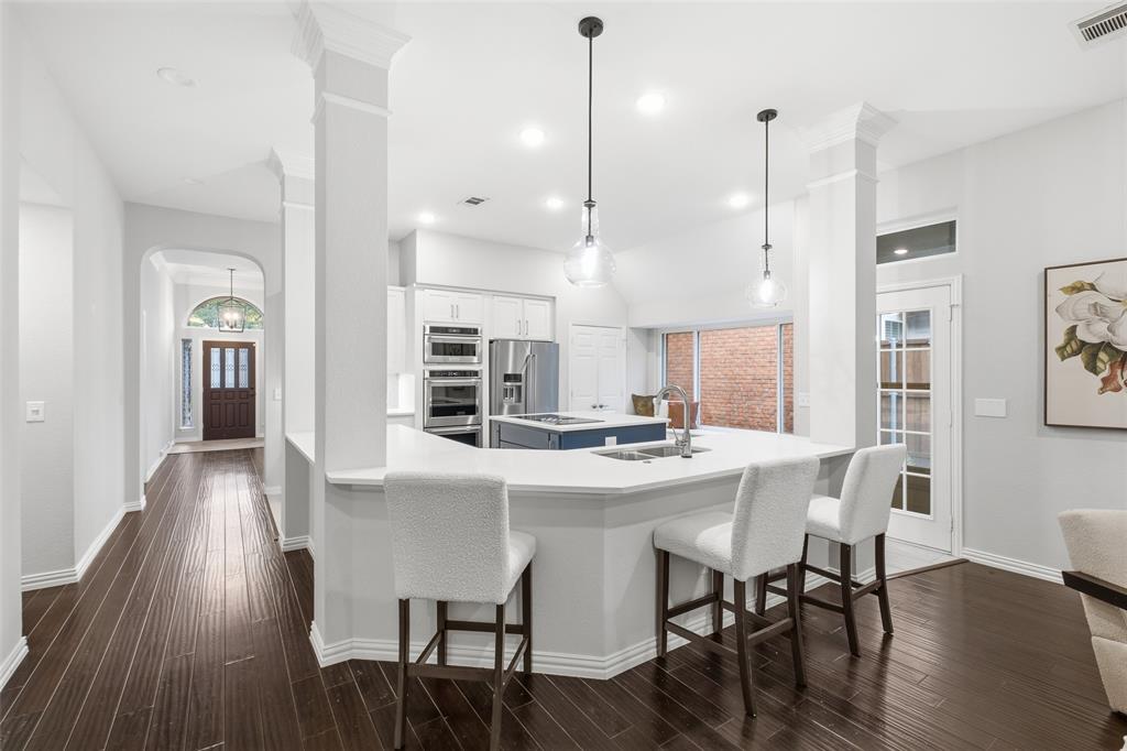 A sweeping breakfast bar wraps the kitchen in seating space, with sightlines all the way to the front door. Made for gathering.