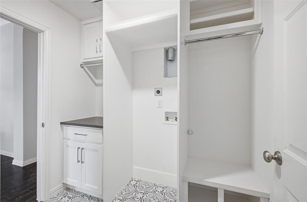 A thoughtfully designed utility room with built-in cabinetry, a counter, patterned tile and a built-in drop zone with bench and hanging rod.