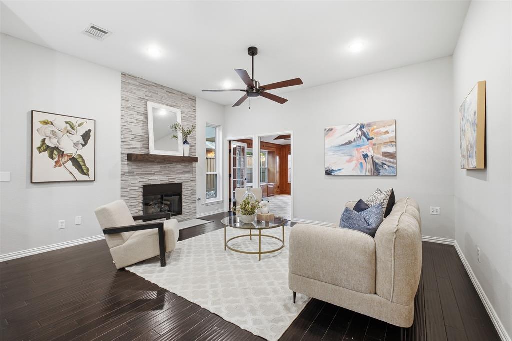 The stone fireplace anchors a living room designed for cozy nights in and easy entertaining, framed by tall windows and dark wood floors.
