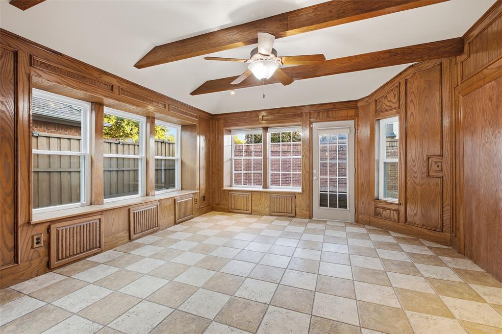 The sunroom is surrounded by windows, with warm wood paneling, beamed ceilings and built-in window seats. A one-of-a-kind retreat for reading, games or morning sun.