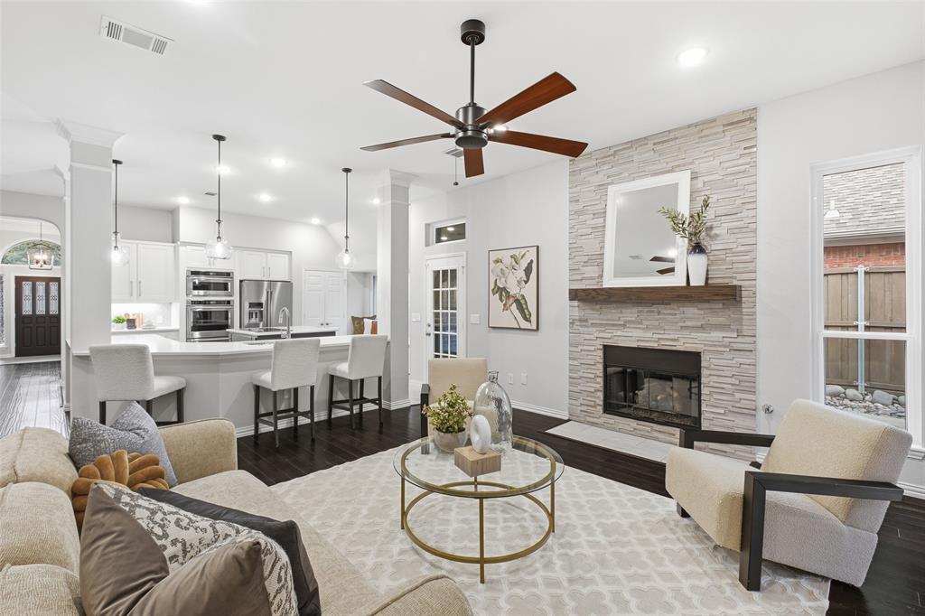The heart of the home: the living room opens straight to the kitchen, with a floor-to-ceiling stacked-stone fireplace, wood-beam mantel and recessed lighting.