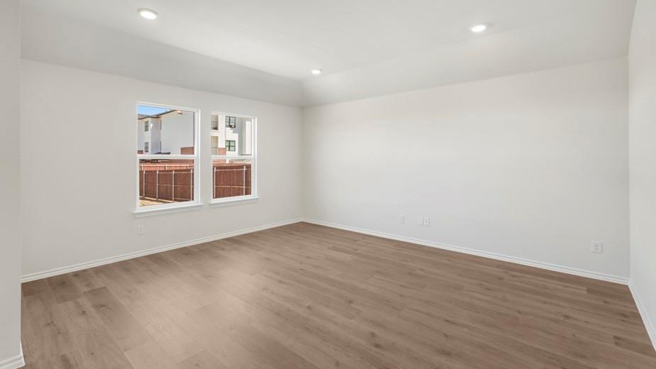 Recessed ceiling lighting illuminates the room with wood-finish flooring and multiple windows