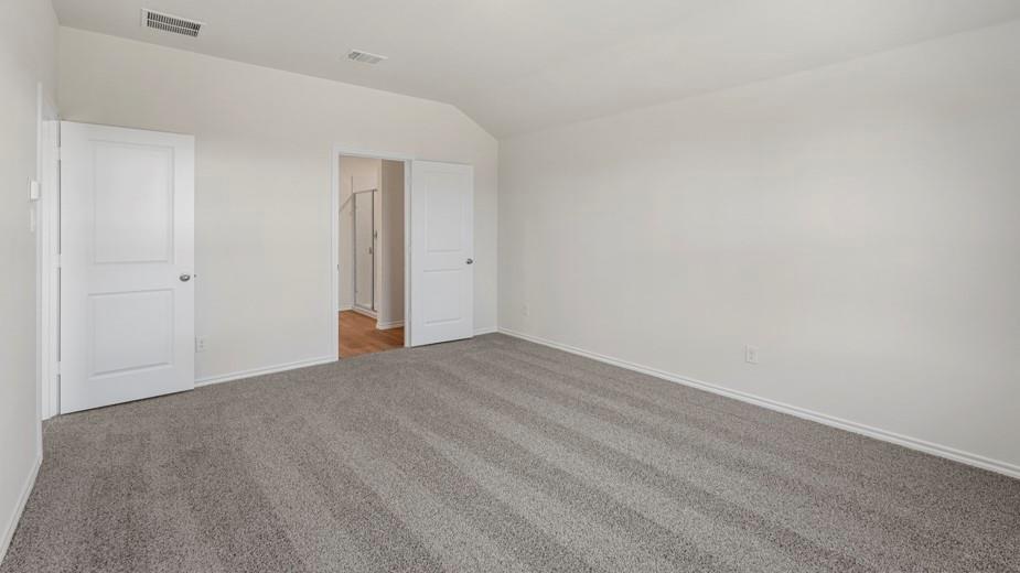 Vaulted ceiling, two paneled doors, light gray carpeting, and light wall finishes