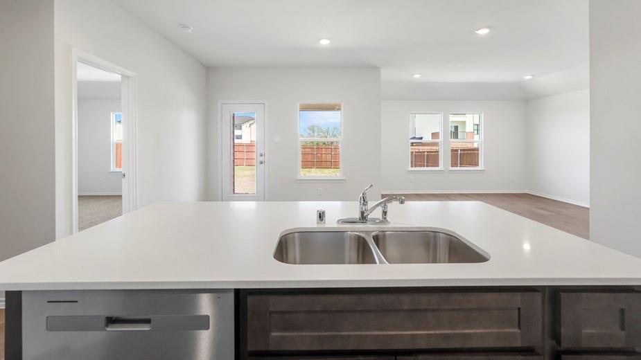 Kitchen island with a dual basin stainless steel sink, stainless steel dishwasher, and dark wood-finish cabinetry
