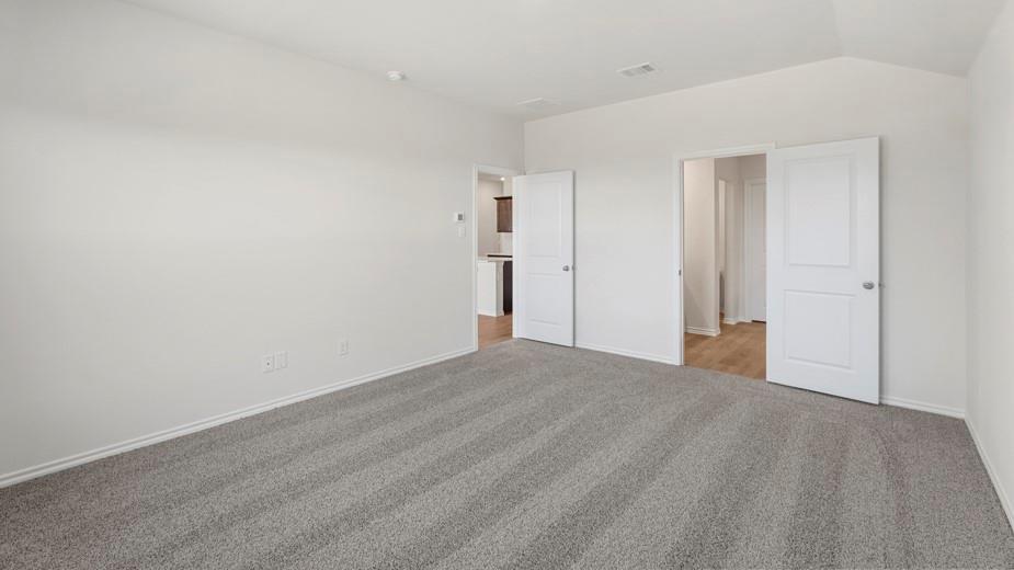 Spacious room featuring neutral carpeting, white walls, and vaulted ceilings