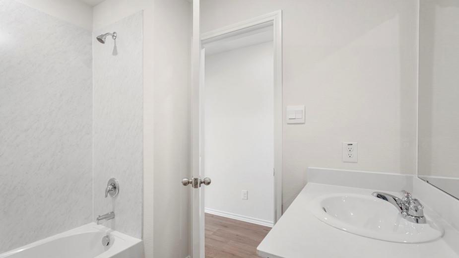 Contemporary bathroom featuring a white bathtub, integrated shower, chrome fixtures, and a vanity with an integrated sink