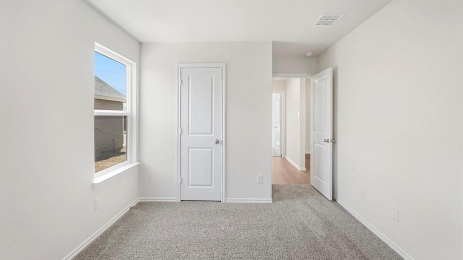 Wall-to-wall carpeting, white interior paint, white trim, white door with silver-tone hardware, and a window with white framing