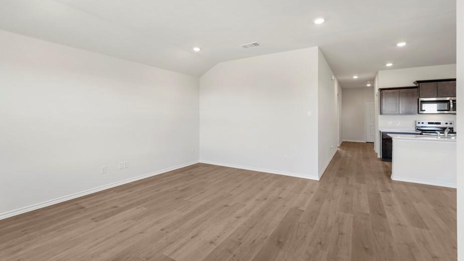 Wood-finish flooring, recessed lighting, white walls, dark wood-finish cabinetry, and stainless steel appliances