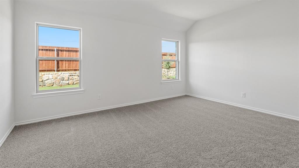 Bright room featuring neutral carpeting, white walls, two windows, and a vaulted ceiling