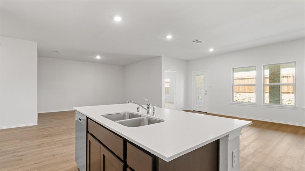 Kitchen island featuring a double-basin stainless steel sink, a chrome faucet, and integrated dishwasher