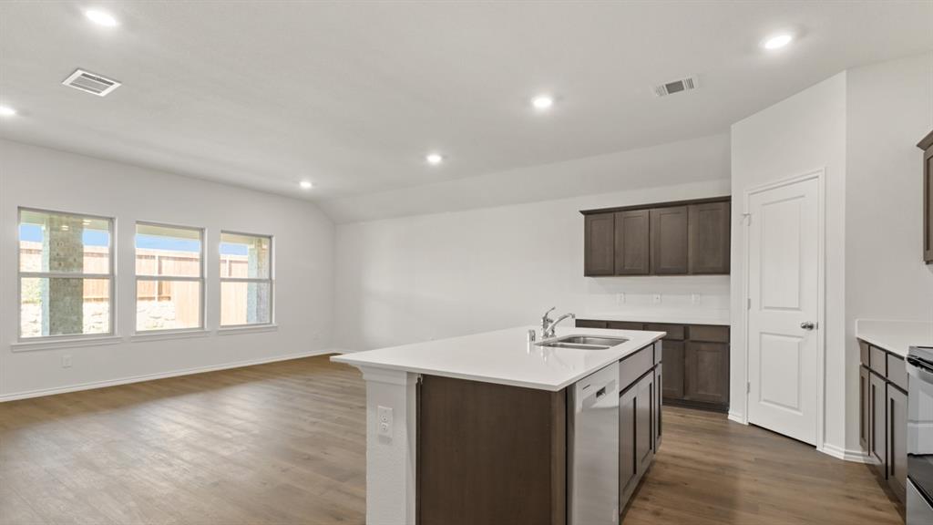 Kitchen island with an undermount sink, a white countertop, and dark wood-finish cabinetry