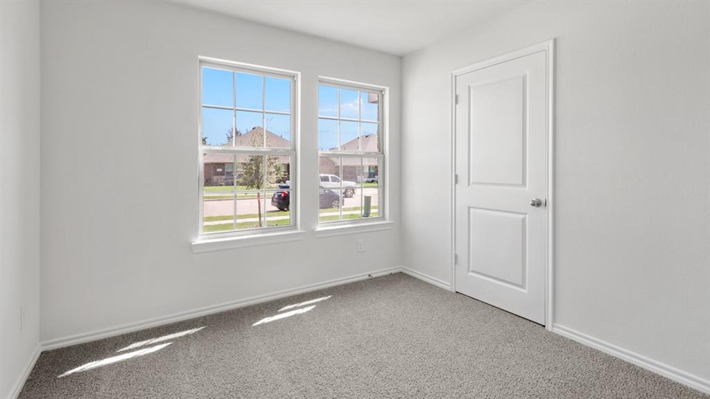 Room featuring two windows with white trim, gray textured carpet, white walls, and a two-panel interior door with a silver knob