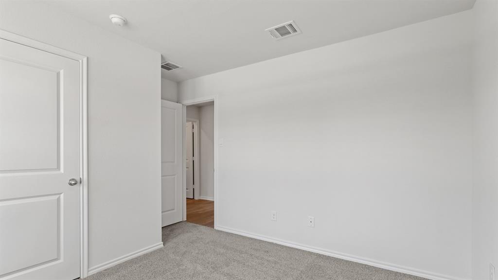 Carpeted room featuring light gray walls, white baseboards, and a white two-panel interior door