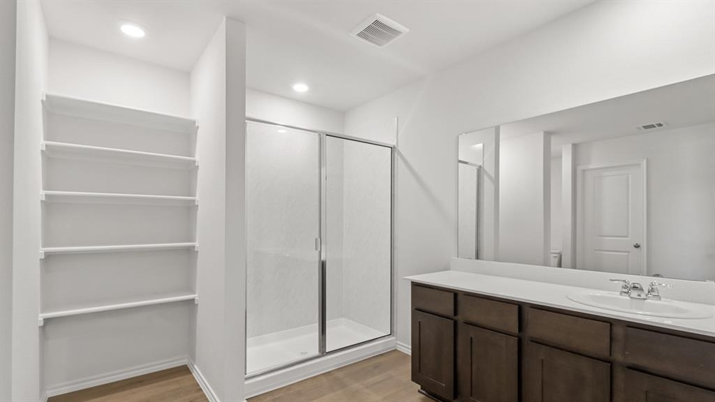Contemporary bathroom featuring a spacious vanity with dark wood-finish cabinetry, a large integrated sink, and an expansive wall-mounted mirror