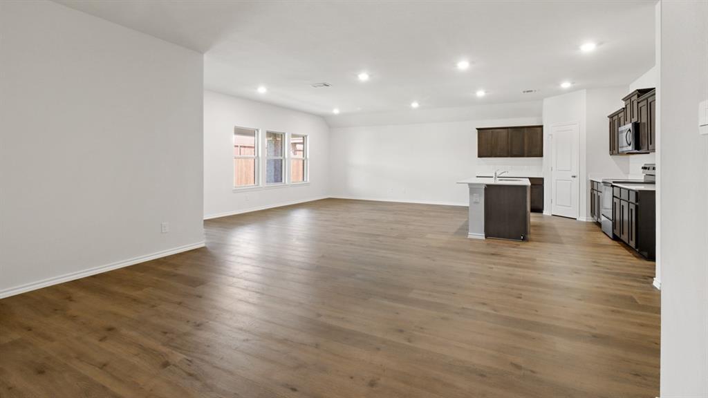 Expansive open-concept room featuring wood-finish flooring, recessed lighting, and a kitchen area
