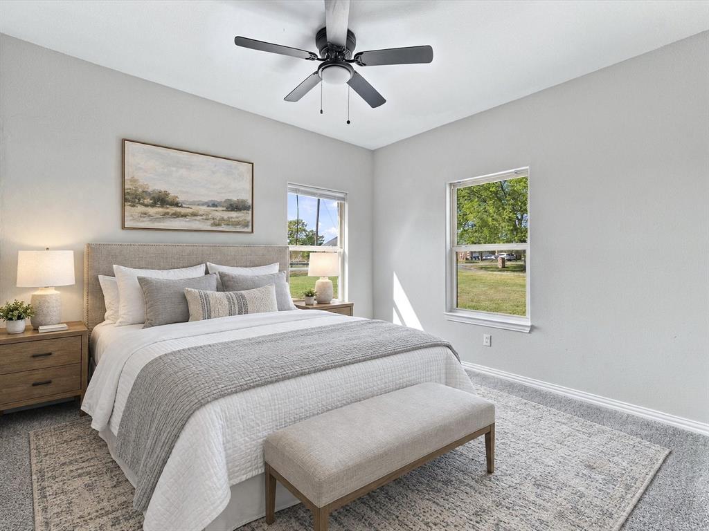 Neutral-toned room with plush carpeting, dual-pane windows, and a matte black ceiling fan with integrated lighting