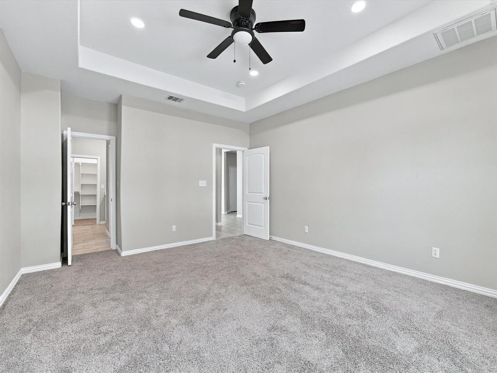Room featuring a tray ceiling, recessed lighting, neutral carpeting, and a multi-blade ceiling fan