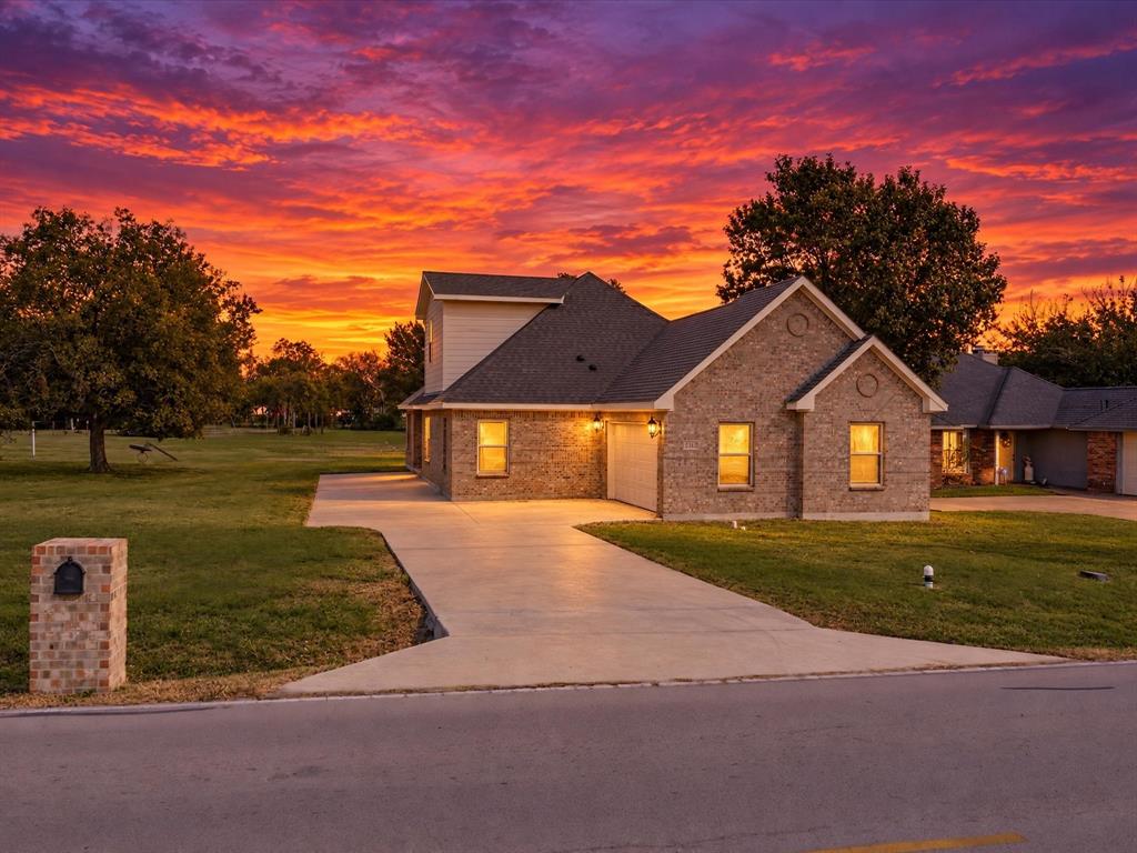 Brick exterior residence featuring a multi-gabled roofline, concrete driveway, and matching brick-pillar mailbox