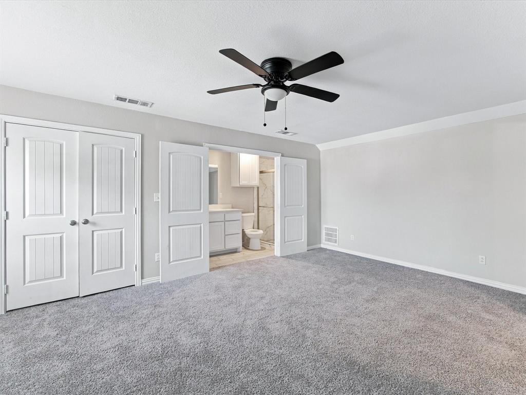 Upstairs secondary Primary Bedroom with neutral wall-to-wall carpeting, crisp crown molding, double-panel interior doors, and a centrally mounted ceiling fan with integrated lighting